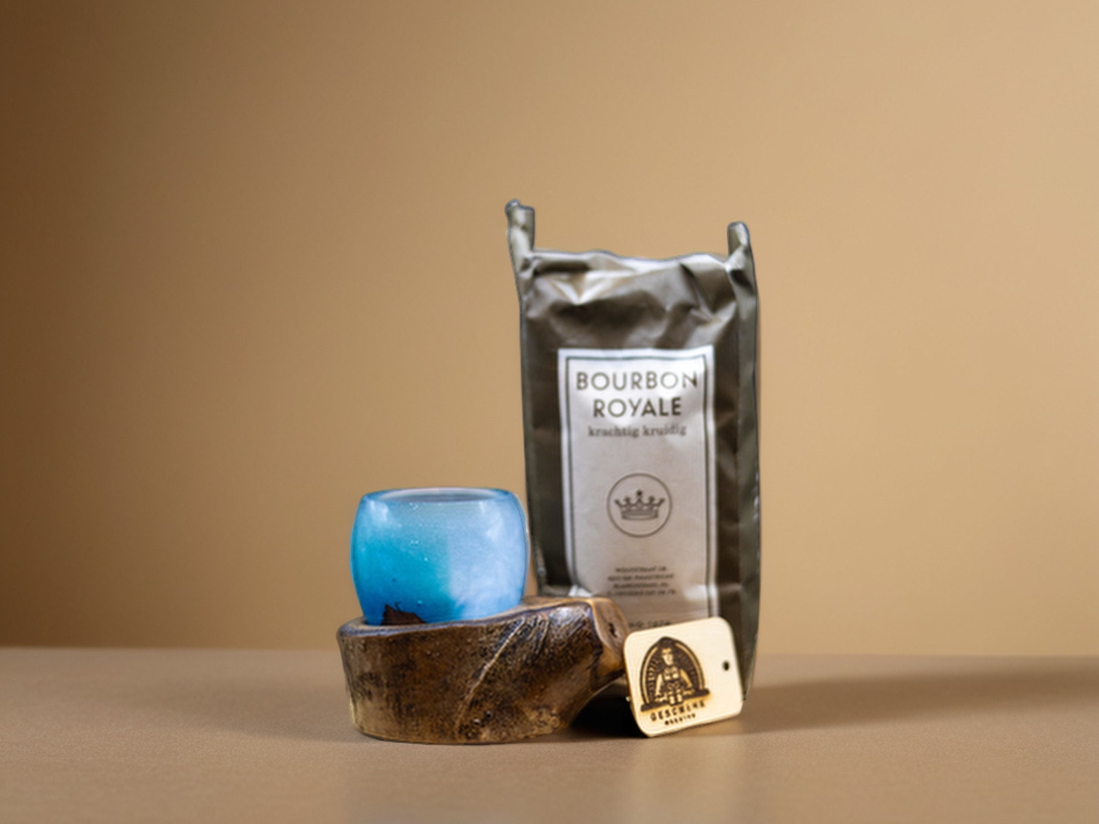 Cadeauset met een blauw glazen espressokopje op een houten voet en een zak koffie, met het kaartje van De Geschenk Meester