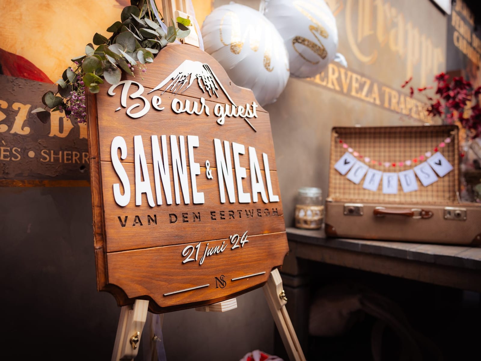 Houten welkomstbord voor een bruiloft, met opgelegde letters en de trouwdatum