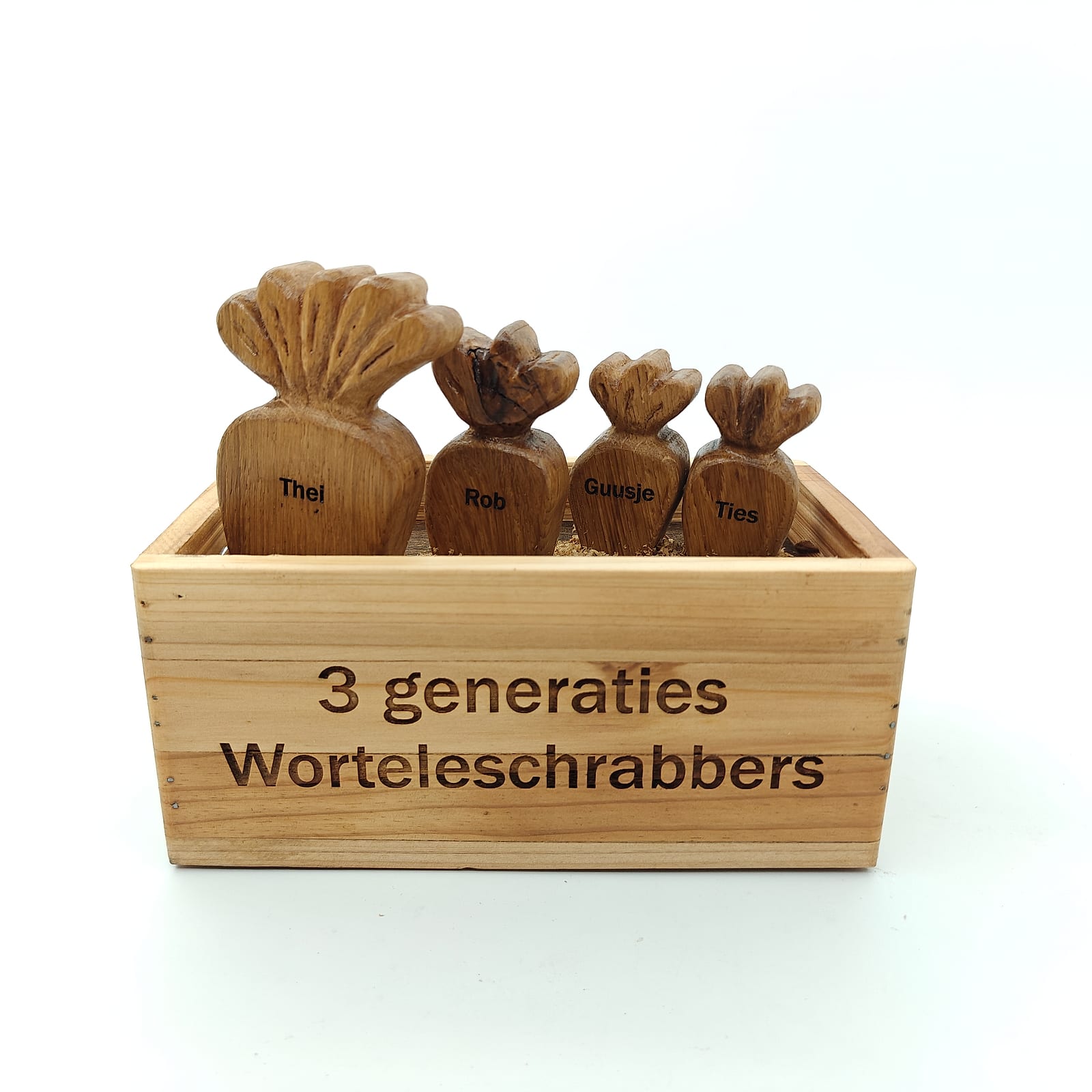Vier houten wortels met gegraveerde namen in een kistje met de tekst 3 generaties Worteleschrabbers