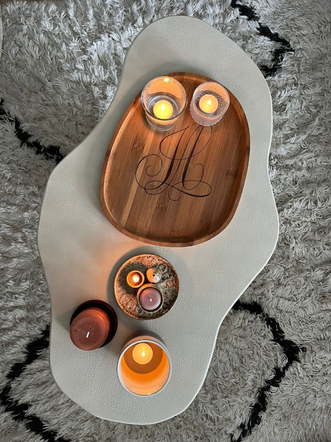 Bamboe dienblad met een gegraveerd monogram, met waxinelichtjes op een salontafel